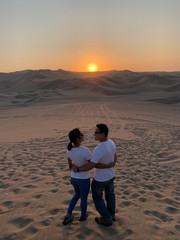 Fototapeta na wymiar Couple enjoying the view of beautiful sunset at Huacachina Oasis in Peru