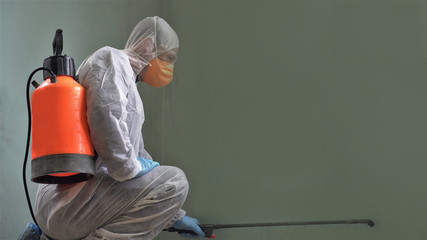 Coronavirus Pandemic. A disinfector in a protective suit and mask sprays disinfectants in the room....