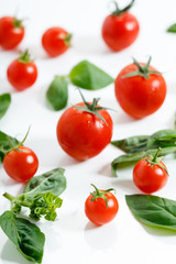 red cherry tomato and basil leaf on white background