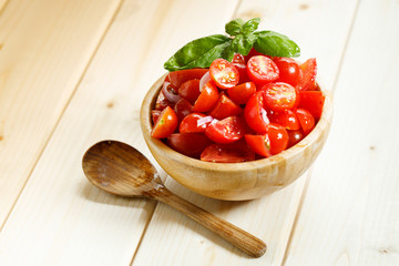 red cherry tomato and basil leaf on wooden bowl on wooden background