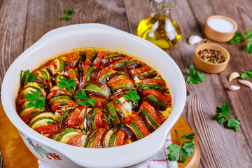 Baked vegetable ratatouille with mozzarella cheese in white oven pan.