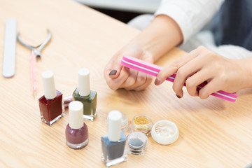 Obraz na płótnie Canvas A young woman paints her own nail polish at home