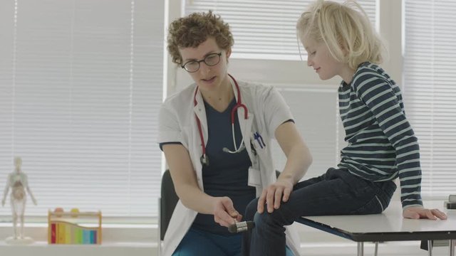 Doctor Testing Girl'S Reflexes With Reflex Hammer On Knee