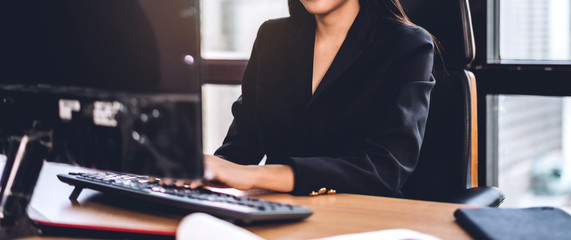 Confident asian businesswoman relaxing looking at technology of desktop computer while sitting on...