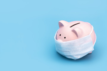 Pink piggy Bank stands on a blue medical background in a medical mask, on the right there is an...