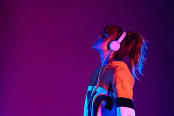 Foto op Aluminium Happy igen teen hipster pretty fashion girl model wear stylish glasses headphones enjoy listen new cool music mix stand at purple studio background in trendy 80s 90s club party light, profile view © insta_photos