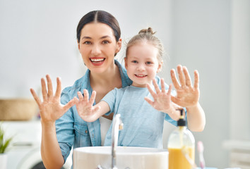 girl and her mother are washing hands