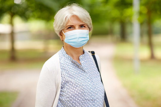 health, safety and pandemic concept - portrait of senior woman wearing protective medical mask for protection from virus in park
