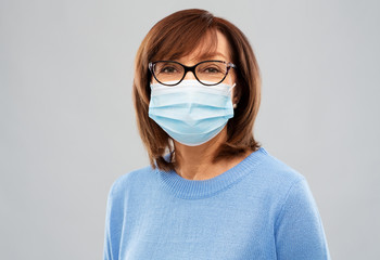 health, safety and pandemic concept - portrait of senior woman in glasses wearing protective...