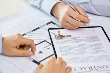 real estate business, sale and people concept - male realtor's hands and customers signing property purchase contract at office