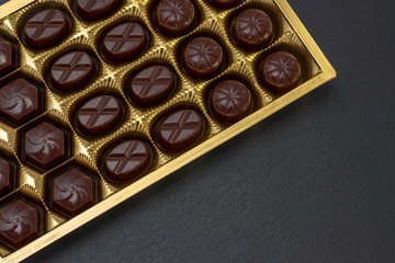 chocolate candies in a box on a black background. dark photo, mood.