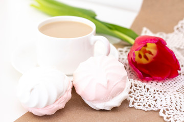 marshmallows, tea or coffee with milk and a tulip flower. on a light background. delicate breakfast, breakfast in bed. for the beloved. Surprise.