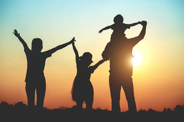 Silhouette of a family comprising a father, mother and two children happy family the sunset.Concept of friendly 