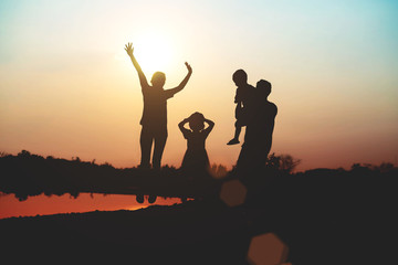 Silhouette of a family comprising a father, mother and two children happy family the sunset.Concept of friendly 