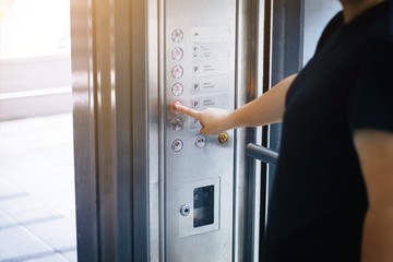 Woman use finger presses the elevator button - obrazy, fototapety, plakaty