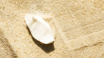 Fototapeta na wymiar Sunscreen cream smudge on sand background with copy space. Summer skincare. Smear moisturizer lotion, above