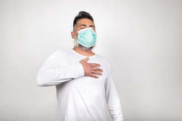 Sick man with medical mask presenting symptoms of coronavirus on white background.