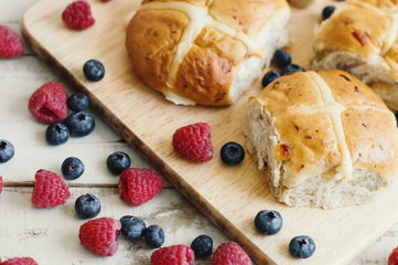 Traditional Easter pastry: homemade hot cross buns srved with fresh blueberry and raspberry