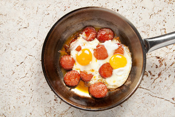 Copper pan with fried egg and sausage