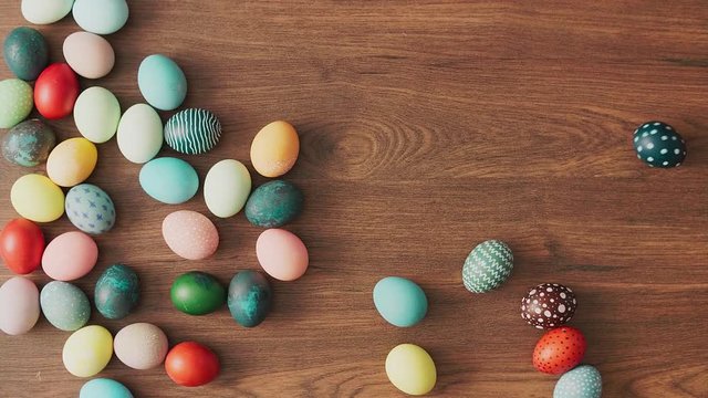 Colorful Easter eggs rolling on wooden table. Easter holiday decorations, Easter concept background.