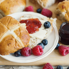 Traditional Easter hot cross buns with butter, jam, blueberry and raspberry. Easter season