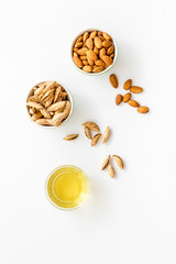 Almond oil - for cooking - in glass bowl near nuts on white background top-down