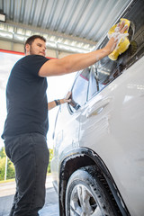 man cleaning car with yellow sponge. carwash concept