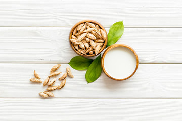 Alternative milk made from almond. Drink near unpeeled on white wooden table top-down