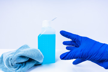 A hand with blue nitril gloves reaching out for a bottle of disinfectant