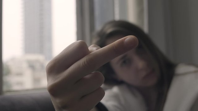 Beautiful girl showing the middle finger.  an annoyed angry woman. close up. out of focus.