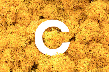 Letter C on a yellow vegetable background.