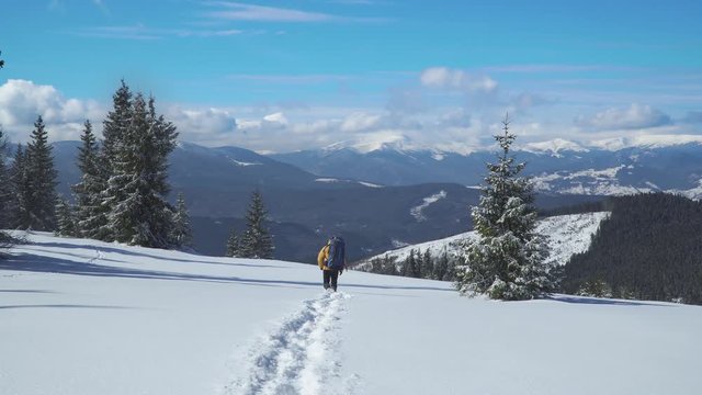 A man with a backpack travels in the mountains in winter. Carpathian mountain range. The concept of travel and active lifestyle. 4K