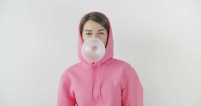 girl dressed in pink hoodie blowing bubblegum