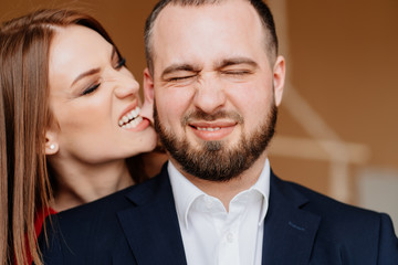 girl in red dress and man in suit and bites on ear