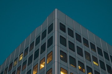 Modern aluminium facade of an office building with cold metal panels and yellow windows inside. Cool and warm photo of a house.