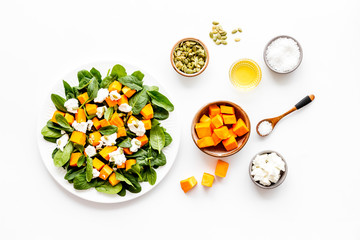 Salad with pumpkin and basil - near ingredients - on white background top-dow