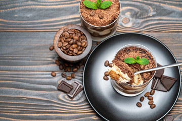 Classic tiramisu dessert in a glass cup on wooden background