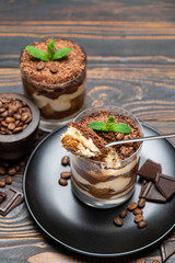 Classic tiramisu dessert in a glass cup on wooden background