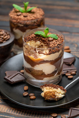 Classic tiramisu dessert in a glass cup on wooden background
