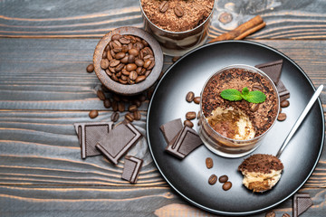 Classic tiramisu dessert in a glass cup on wooden background