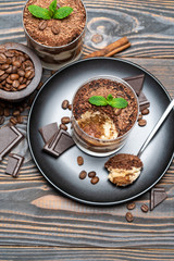 Classic tiramisu dessert in a glass cup on wooden background