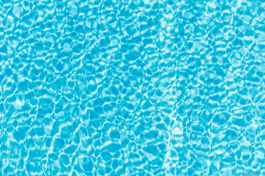 Surface of blue shining swimming pool water ripple and sun reflection. Perfect as a background for summer, vacation, calmness, serenity or any other idea.