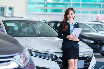Fototapeta na wymiar Asian young woman in a car Rental Service Assistant/Car sales concept in show room.