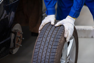 mechanic in uniform is check the quality of rubber wheels that have been used. while working in car repair center. © tong2530