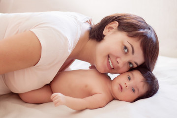 Obraz na płótnie Canvas Beautiful mom and baby lie on white plaid, smiling