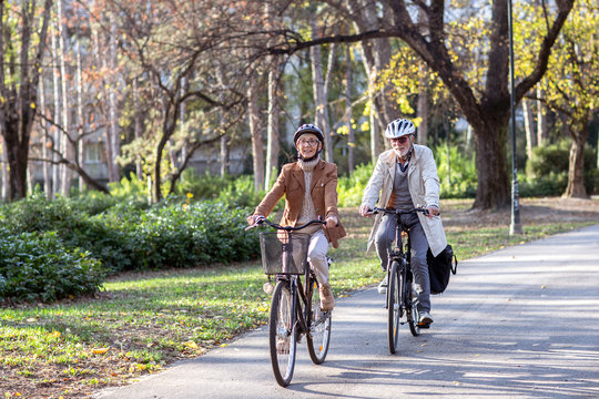 Senior Couple With Bycicles And Helmets In Park