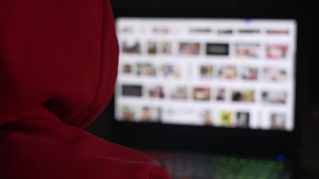 Man in the red hoodie secretly watching porn sites at night.
