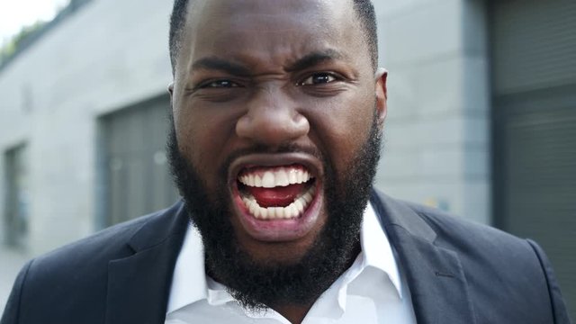 Businessman yelling at camera on street. Nervous male manager screaming outdoors