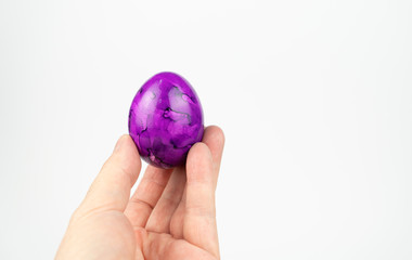 One lilac Easter egg holding in hand, white background with copy space