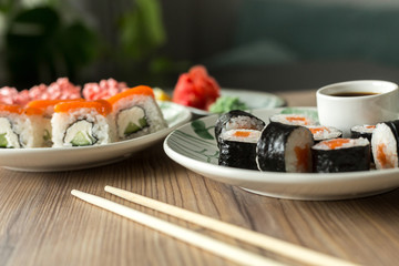 Set sushi roll California and sushi Maki with salmon on a wooden table. Asian food Sushi and soy sauce in a bowl, ginger and lemon. Sushi menu. Japanese food. hand-made fresh sushi rolls